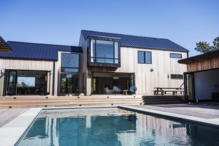 Bi-fold doors connect the main residence to the backyard, which features a large swimming pool, a 200-square-foot pool house, and an outdoor kitchen.