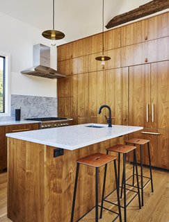 European walnut lines the custom kitchen, which is outfitted with Blum and Hafele hardware, a Solna faucet by Brizo, and pendants by Danish studio Frama. The range is Thermador.