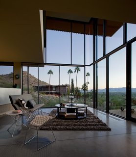 With floors made of cork and concrete, the house is surrounded by substantial panels of translucent glass. The double-height living room acts as a collective open space that looks out to the dramatic views of the desert. 