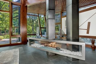 Designed by architect David Jameson in the heart of Bethesda, Maryland, this sculptural residence is filled with bespoke elements that are made up of wood, metal, stone, and glass. The centralized fireplace divides the open living space into two separate seating areas, without closing them off from one another. 