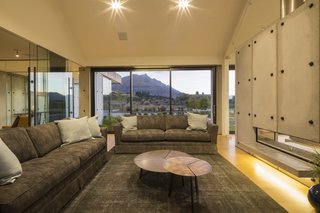 Constructed of precast concrete panels, this contemporary home in Queenstown, New Zealand was named the winner of the Gold and Lifestyle Awards at the 2015 Registered Master Builder House of the Year awards. Dividing the living and dining spaces, the slab fireplace runs the length of the living room and contrasts smoothly with soft timber woods that are utilized throughout the rest of the home. 