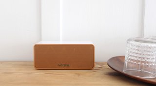 The rose gold Sound Piece Mini in rose gold is shown here next to a grouping of glasses to show scale (6.5 in. wide x 2.8 in. high x 2.75 in. deep). With a battery lifespan of up to 15 hours, it also features an emergency power bank for on-the-go smartphone charging. 