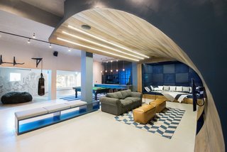 A movie-watching seating area with a curved timber "wave" cascades from the ceiling to the floor. 