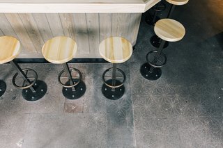 Customers are given the freedom to seat themselves with a "self-regulating line" concept. The stained concrete floors feature a subtle stencil pattern and a rough, weathered texture that's reflected throughout the rest of the space.