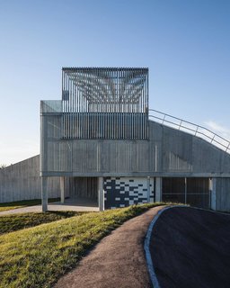 The ramp structure supports two different starting points—one five-meter-high version for beginner cyclists, and one 10-meter-high version for those who are more experienced. Below the ramp, you'll see a treatment of colored concrete blocks that conceal an area for storage.