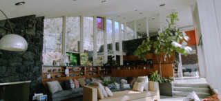 Looking into the living space, you can see the colored stained-glass window panels and the arch of the roof. When Marmol Radziner began the renovation, they updated the cabinetry with stained walnut and replaced the existing formica countertops with honed, black granite that actually looks like the original formica.