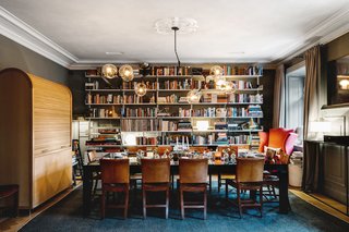 In the formal dining area, guests are invited to make themselves at home. The floor-to-ceiling bookcases create an intimate dining experience, which sits under original decorative ceiling details. 