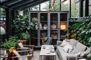 Shown here is the lounge seating vignette in the covered patio/garden area, which is filled with greenery and furniture that's covered with warm textiles.