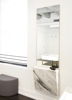 They affixed a chunk of Mountain Calcutta marble to a wall-mounted mirror to hold jewelry during fittings.