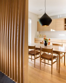 A Toronto-Based Firm Breathes New Life Into a Victorian’s Interior - Photo 1 of 3 - The dining area is separated from the entrance with a custom wrap-around screen that provides privacy without closing the space off completely. The slats are made of CNC’ed wood. 