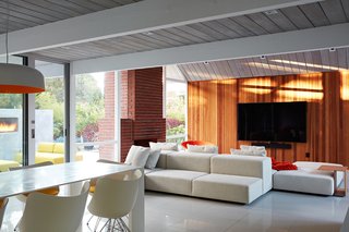 Same Bones, New Materials—A Double Gable Eichler Gets a Dashing Update - Photo 3 of 9 - To satisfy the couple’s desire to combine the kitchen, living, and dining spaces into one large area, they removed any barriers and installed walnut vanities and cabinets for extra storage. They preserved the original brick fireplace. 
