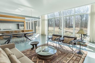 Red Cedar Is the Key Ingredient of This Wooded Cottage For Sale - Photo 3 of 8 - Taking a peek into the combined living area at the center of the house shows the kitchen that’s made up of the same red cedar that’s used throughout the home—as well as laminate marble. 