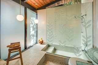 The master bathroom has been updated with George Nelson’s sculptured tiles from Pomona Tile Manufacturing Co. The shower wall features the "Laurel Leaf" pattern, which is a bas-relief treatment of a single diagonal leaf motif with both raised and recessed areas. The most recent homeowner also installed etched glass to mimic the motif of the tile. 