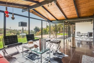 When you enter into the house, you find yourself in an open space that combines the living and dining rooms—and is lined with floor-to-ceiling glass. The dining area is marked by the same aggregate concrete flooring that began in the front of the house. 