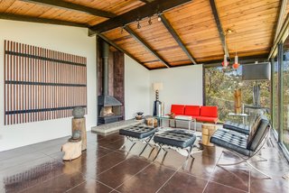 A wall of quarry tile surrounds the freestanding fireplace that takes centerstage in the living room. Cole pointed out that though it's original to the house, its initial orange color has been painted over. 