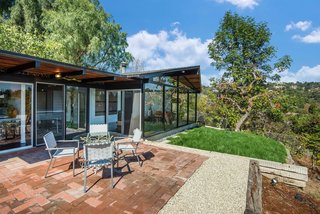 The outdoor space can be accessed directly from the living area and includes a deck, lawn, and a section that’s perfect for an outdoor dining table setup—which sits on top of terra cotta tile and more aggregate concrete floors. 