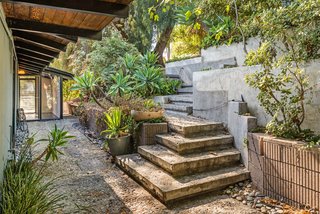 An impressive stone staircase leads down to the entrance of the house. Here, you'll also find an aggregate concrete floor treatment, which continues to be a theme throughout both the interior and exterior. 
