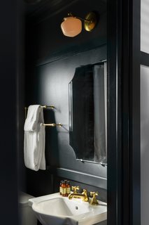 In the moody bathrooms, you’ll find solid brass fixtures, rain showers, chamfered mirrors, and products from C.O. Bigelow Apothecaries. 
