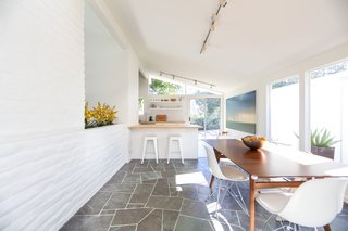 Though the main bones have been kept intact, one of the past owners installed slate flooring in the entryway, hallway, and dining area (shown here)—which leads into the lengthy kitchen. 