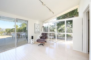 A corner of the open living space looks out to the outdoor living areas through extensive glass, original skylights, and an angular clerestory design—all of which invite natural light in.