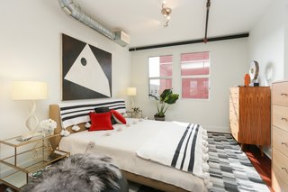 The bedroom is tucked into the loft space and sits under exposed air ducts and pipes—both of which add to the industrial vibe.