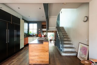 Formerly Home to an Artist and Knitwear Designer, a Commercial Space-Turned-Dwelling Hits the Market - Photo 4 of 10 - On the other end of the dining space is the kitchen, which contains an extensive island that acts as a divider from the pathway that leads to the garden room. One of the many sets of original concrete stairs is seen on the right. 