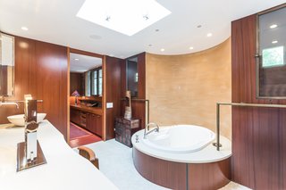 Shown here is one of the double master bathrooms, which holds a new tub that sits in front of a painted plaster wall. The layout and mahogany panels have remained original. 