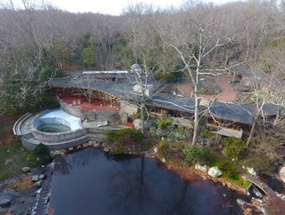 An overhead drone view shows the 15-acre property that also hosts a heated pool, river, tennis court, barn/stable, sculpture path, and rooftop observatory. The original landscaping was designed by Frank Okamura and Charles Middeleer. 