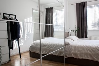 To create more storage and to make the bedroom feel larger, they placed an Ikea wardrobe with mirrored doors next to the bed. The clothing rack on the other side of the compact room is from HAY.