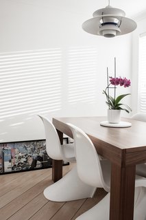 The dining area—which sits in the same open space as the living room and takes in tons of natural light—is marked by a hanging pendant lamp designed by Louis Poulsen. Silvia purchased the extendable dining table from BoConcept and surrounded it with Vitra’s Panton Chairs by Verner Panton. The piece of art leaning against the wall is by Mr. Brainwash, and was acquired when Silvia and her boyfriend visited one of his exhibits together for the first time.