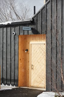 A Modern Mountain Lodge That Will Make You Love Winter Like Never Before - Photo 7 of 13 - The exterior of the structure is wrapped with a board-and-batten facade made of locally-milled wood that's been finished with a dark stain. It’s balanced out by sections of natural pine and cedar.