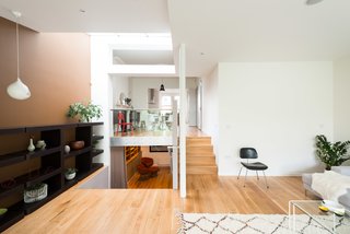 The home's interesting layout becomes clear from this view, which shows the glass balustrade that separates the dining room from the sitting room. The lower steps to the left lead to a media room on the lower ground floor, which then connects to a guest bedroom with an en-suite bathroom.