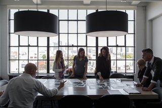 In the main conference room, Hollis and a few members of her team spread out photos and plans over a custom conference table made Christian Hummler. The pendants overhead are designed by Piet Boon for Moooi.