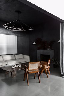 When you first enter the space, you step into a moody entry salon with hand-applied Italian integral color plaster walls and a marble fireplace. Designed to feel welcoming and residential, it’s furnished with midcentury armchairs and a dramatic hanging light fixture by Bec Brittain.