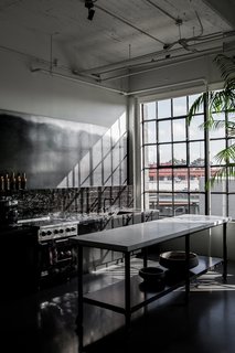 Directly next to the dining area is the dark kitchen, which has a custom island that's made with a metal base and a CoorItalia Calacatta marble top. Designed by Chris French, it’s designed to invite socializing.