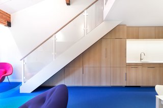 Bright Colors and Sleek White Oak Fill This Playful Lake Tahoe Loft - Photo 3 of 9 - The custom cabinetry is made with bleached rift-cut white oak and is finished with mirror pulls. Created by David Amble Cabinetry, the cabinets were designed to be put to serious use—one holds extra folding dining chairs while another hides a Murphy bed.
