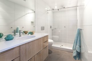 Bright Colors and Sleek White Oak Fill This Playful Lake Tahoe Loft - Photo 6 of 9 - The bathroom was completely remodeled and features large glass tiles that read as one single surface material. The floors are made with unfinished poured concrete.