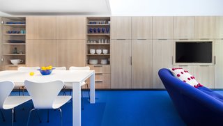 Bright Colors and Sleek White Oak Fill This Playful Lake Tahoe Loft - Photo 9 of 9 - Because of the loft’s specific layout, they decided to maximize the space by creating as much storage as possible on the available walls. Shown here is one of the walls that’s lined with flush-mounted cabinets by David Amble Cabinetry. The dining table is surrounded by Arne Jacobsen Series 7 Chairs.