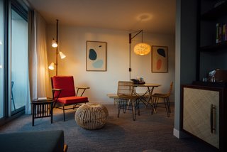 The rooms also include custom lounge chairs, tables, spring pole lamps, and rattan chairs.