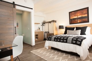 A New Modern Hotel in San Diego Offers Surfing Adventures and Local Hospitality - Photo 5 of 10 - In order to provide a durable and hardy surface for beachgoers, the floors are lined with tile that looks like sun-bleached wood. To create a fun, casual, and beachy vibe, the team introduced barn doors, white beach rock tile in the shower, retro-looking light green sinks, and open closet systems made with wood and iron.