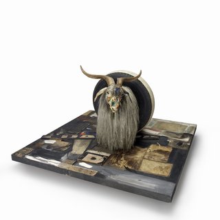 Monogram 1955-59 – Combine: oil, paper, fabric, printed reproductions, metal, wood, rubber shoe-heel, and tennis ball on two conjoined canvases with oil on taxidermied Angora goat with brass plaque and rubber tire on wood platform mounted on four casters.