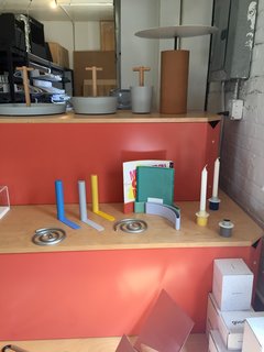 A selection of Good Thing favorites, including the Slim bookends by Kenyon Yeh, Spiral trivet set and Paper Display by Sam Anderson and Jamie Wolfond, and Anderson's Field candle holders, sit side-by-side on a colorful display. 