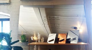 A trio of the brand's Easy mirrors and a group of Gather vases sit on a shelf in front of a large logo-branded mirror. 