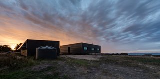 14 Totally Off-the-Grid Cabins - Photo 5 of 14 - A rugged exterior of spotted gum cladding and corrugated Spandek material shelter the prefabricated, off-the-grid getaway.