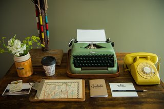 A working vintage typewriter and telephone top the antique desk.