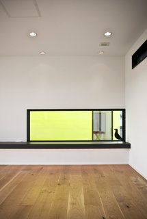 This Minimal Japanese Getaway Was Built for Surfing - Photo 4 of 7 - Hints of the sunny accent paint can be seen throughout the house, like this glimpse of the courtyard seen through the bedroom's YKK AP window.