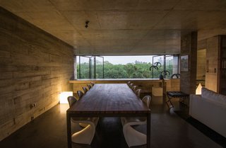 Expanses of low-e glass open to views of the nearby greenery. Designed by the architect, these 15-foot-tall panes virtually disappear when moved to the side.