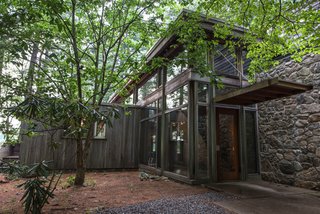 A glass-walled addition joins Marcel Breuer's minimalist Chamberlain Cottage. Part of the original house extends from the left of the structure. 