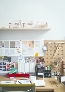 A shelf of models sits over a design station layered with inspiration. 