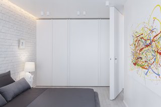 In the bedroom, storage was designed to fade away into the background, while a colorful painting pops against the white backdrop.